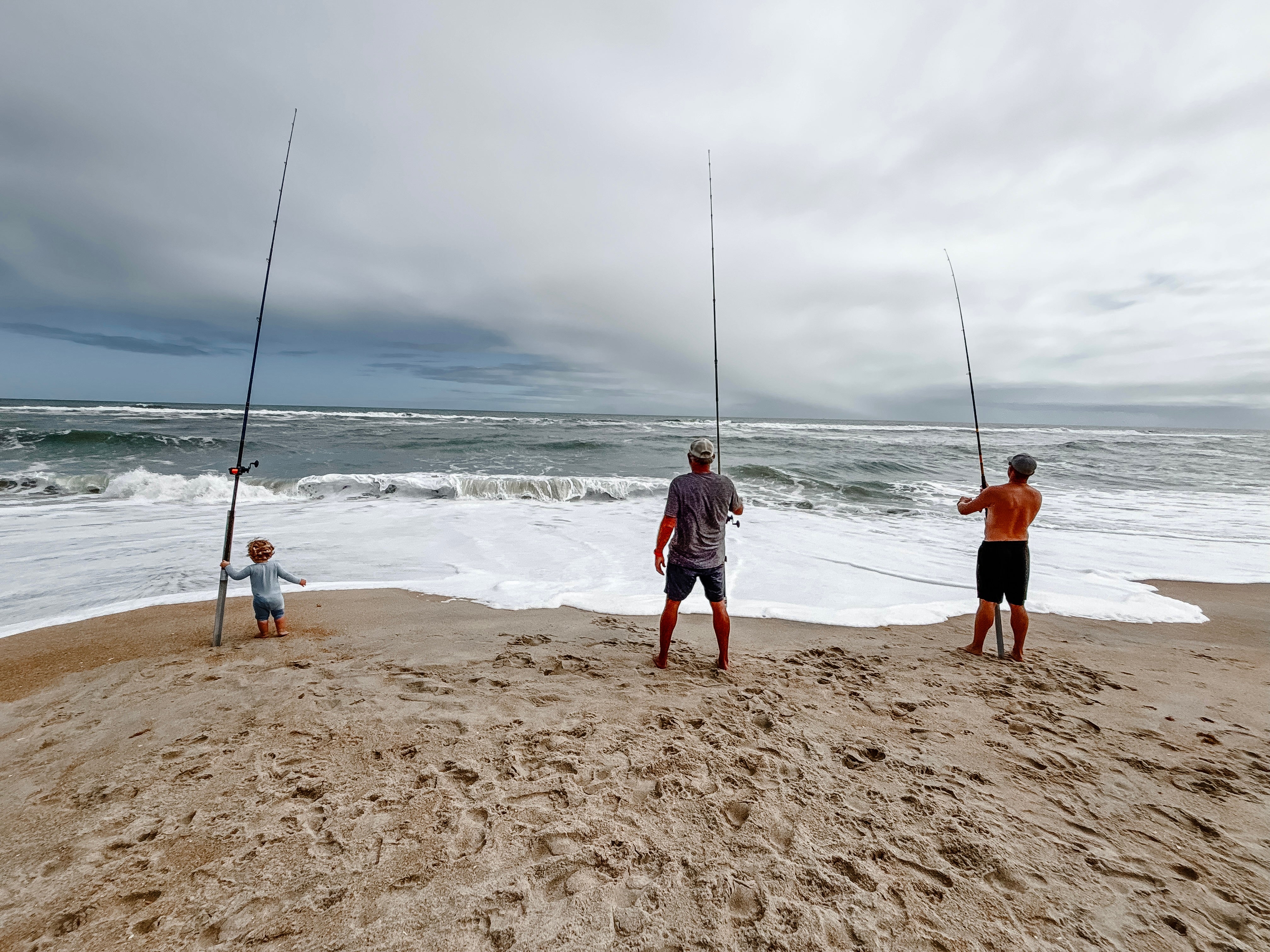 Two men and an infant fishing on the beach at Cape Hatteras National Seashore