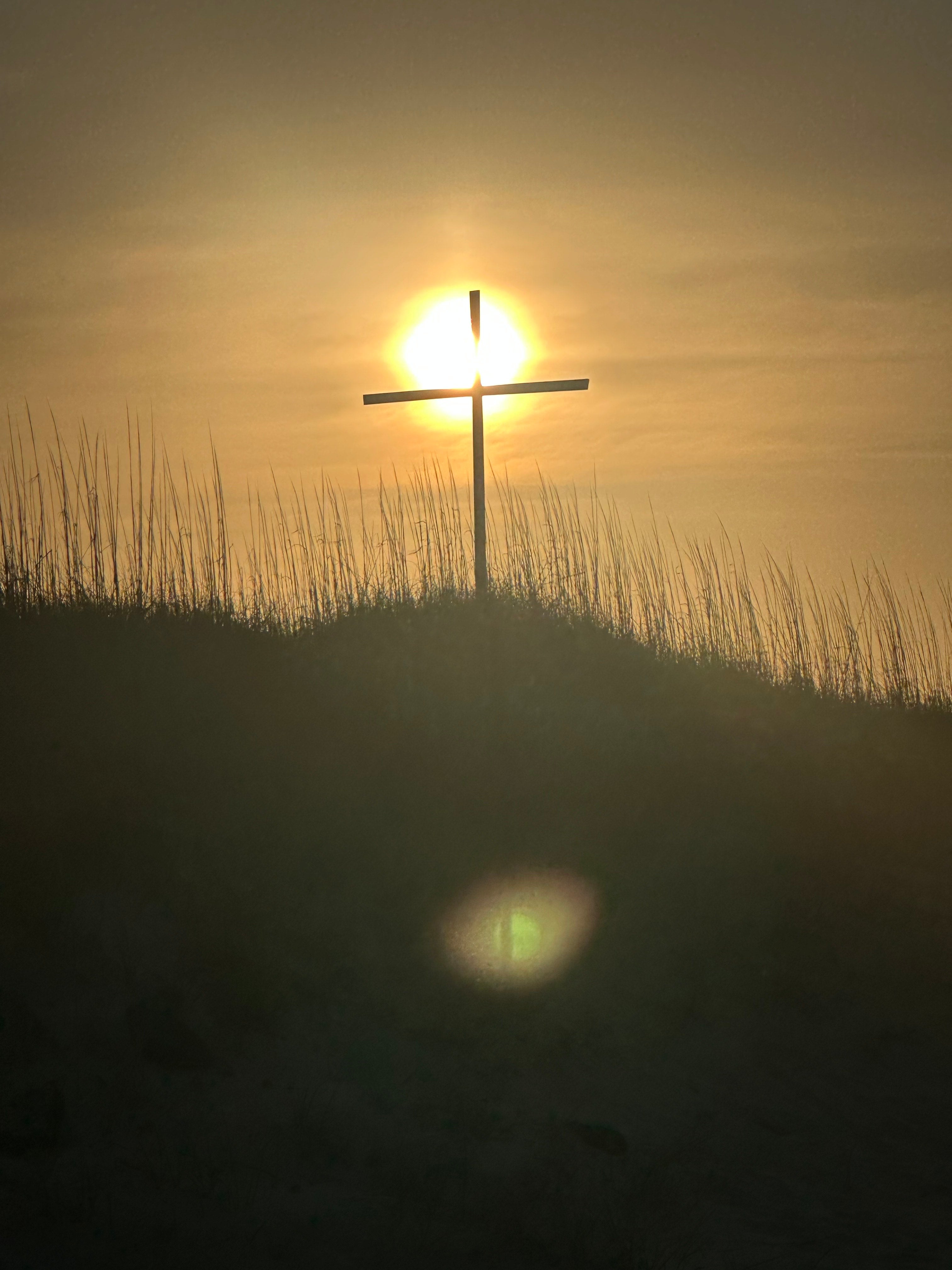 Cross with sunrise in the background at Buxton NC Beach