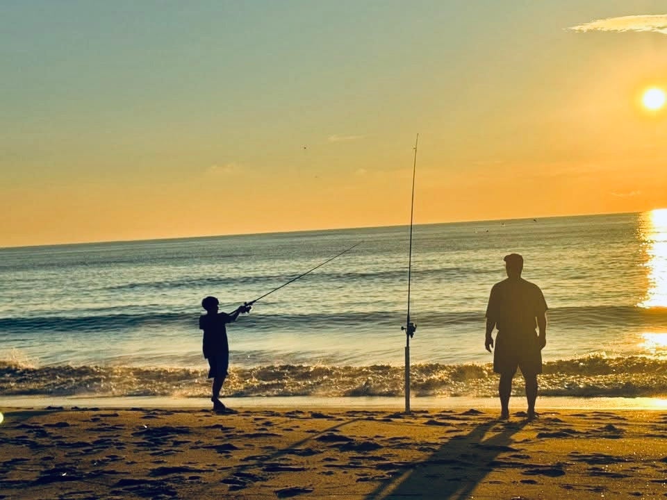 Child fishing on the beach with adult during sunrise at Cape Hatteras National Seashore Rodanthe NC