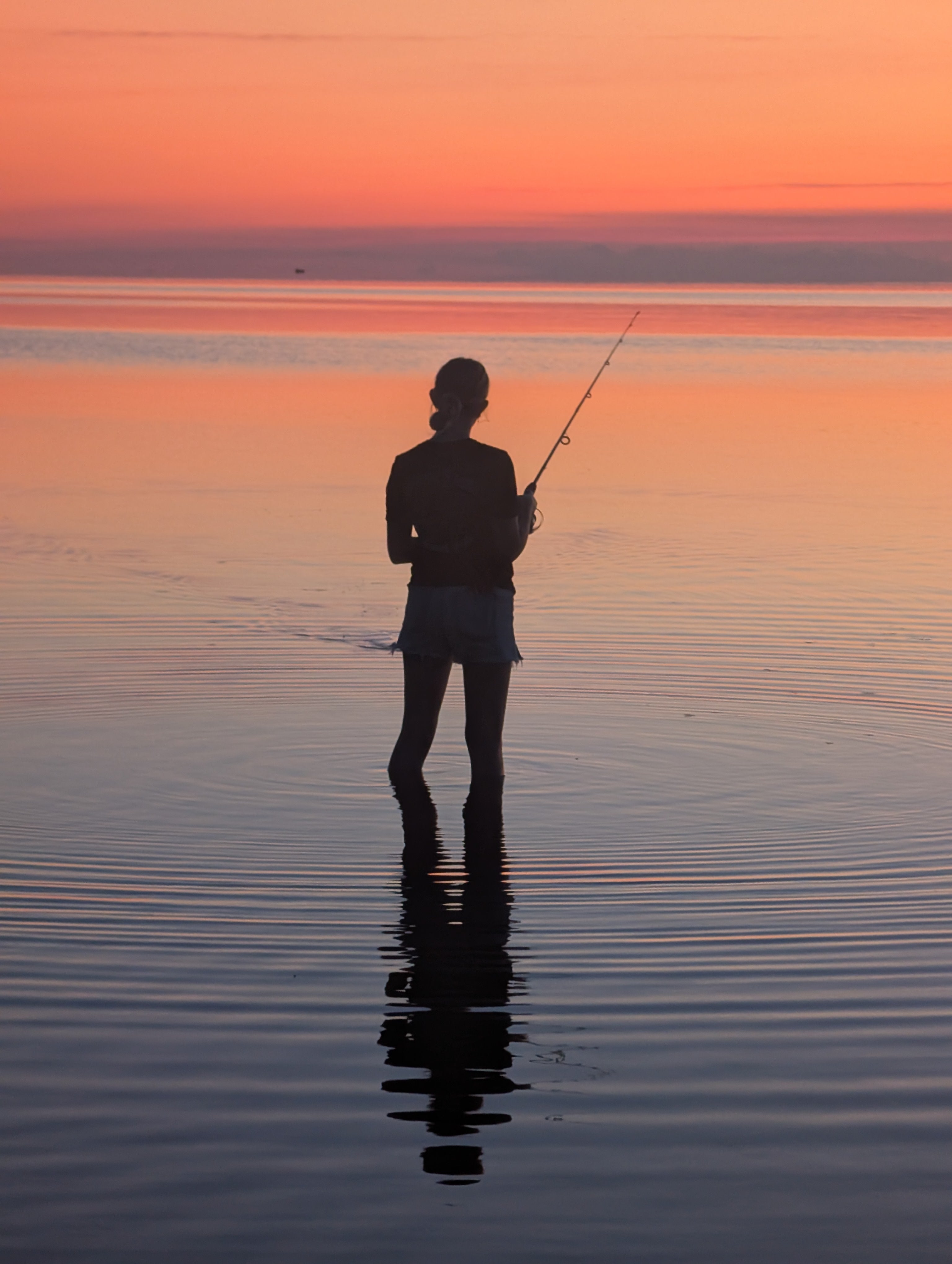 silhouette of a girl fishing in the pamlico sound at sunset